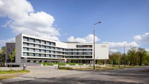 ein großes weißes Gebäude mit einer Straße davor in der Unterkunft Hunguest Hotel Sóstó in Nyíregyháza