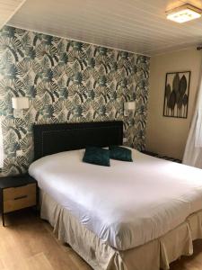 een slaapkamer met een groot wit bed met een muur bij Hotel du Levant in Castellane