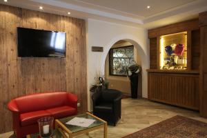 uma sala de estar com uma cadeira vermelha e uma televisão na parede em Hotel Bärenbachhof - Joker card included in summer em Saalbach-Hinterglemm