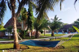 a hammock in a yard with palm trees at Dadida‘s Pool Cottage in Diani Beach