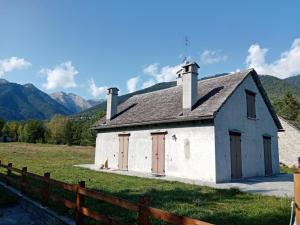 una vecchia chiesa bianca con montagne sullo sfondo di BAITA SIBERIA a Craveggia