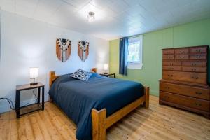 a bedroom with a blue bed and a dresser at Refuge du Massif - Halte au cœur du village in Saint-Philémon