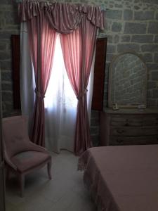 um quarto com uma cama, uma cadeira e uma janela em Casa Mene' em Arzachena