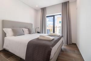 a bedroom with a bed with white sheets and a window at Roots Hotel in Faro +37 photos