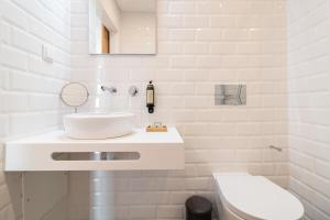 a white bathroom with a sink and a toilet at Roots Hotel in Faro