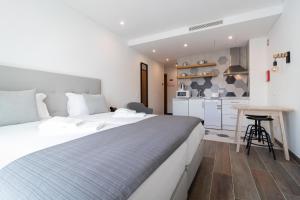 a bedroom with a large white bed and a kitchen at Roots Hotel in Faro