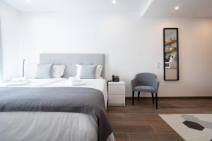 a bedroom with a bed and a chair and a mirror at Roots Hotel in Faro