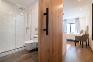 a bathroom with a toilet and a glass shower at Roots Hotel in Faro