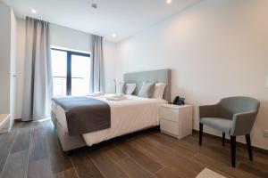a bedroom with a bed and a chair in it at Roots Hotel in Faro
