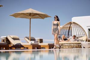 a woman standing in front of a swimming pool at Nival Boutique Hotel in Sifnos