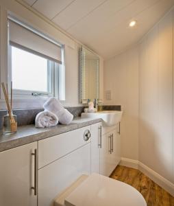 Baño blanco con lavabo y espejo en The Pond Lodges Barstobrick en Ringford