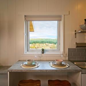 una cocina con una mesa con dos tazones y una ventana en The Pond Lodges Barstobrick en Ringford