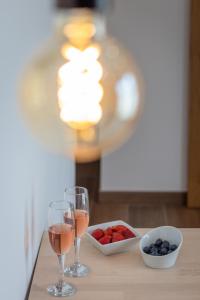 two glasses of wine and a bowl of fruit on a table at Roots Hotel in Faro