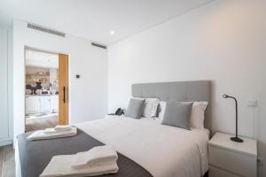 a white bedroom with a large bed and a kitchen at Roots Hotel in Faro