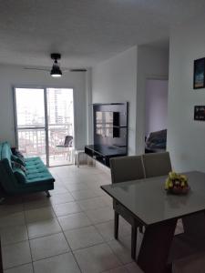 een woonkamer met een tafel en een televisie bij Lindo Apartamento Novo Praia Grande Ocian 50 Metros da Praia in Praia Grande