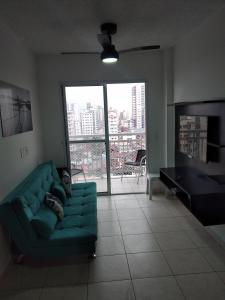 een woonkamer met een groene bank en een groot raam bij Lindo Apartamento Novo Praia Grande Ocian 50 Metros da Praia in Praia Grande