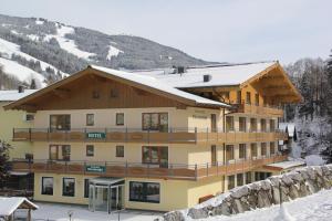 a large building with snow on the ground at Hotel Bärenbachhof - Joker card included in summer in Saalbach Hinterglemm