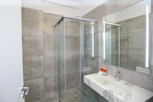 uma casa de banho com um chuveiro, um lavatório e um espelho. em Regina Garden Vlore em Vlorë
