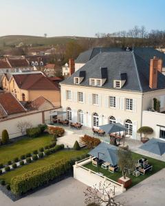 - une vue aérienne sur une grande maison blanche avec des tables et des parasols dans l'établissement Les Chambres du Champagne Collery, à Ay