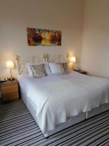 1 dormitorio con 1 cama blanca grande y 2 lámparas en Edendale House en Southport