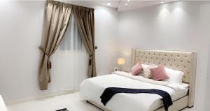 Habitación blanca con cama con almohadas rosas en مساكن الدار 8, en Abha