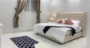 Habitación blanca con cama con almohadas rosas en مساكن الدار 8, en Abha