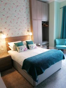 - une chambre avec un grand lit et une couverture bleue dans l'établissement Edendale House, à Southport