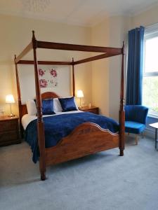 a bedroom with a canopy bed and a blue chair at Edendale House in Southport