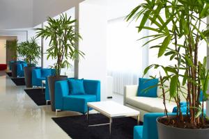 a lobby with blue chairs and palm trees at Luna Miramar Club in Albufeira