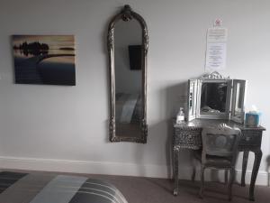 a mirror on a wall next to a table with a chair at South Beach B & B in Lowestoft