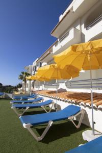 vier ligstoelen en parasols naast een gebouw bij Luna Miramar Club in Albufeira