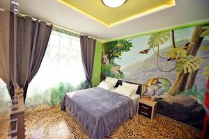 ラザレフスコエにあるMalibu Guest Houseのベッドルーム1室(壁に絵画が描かれたベッド1台付)
