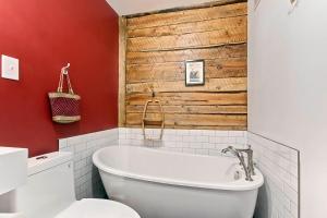 baño con bañera blanca y pared de madera en Les Appartements du 790, en Quebec