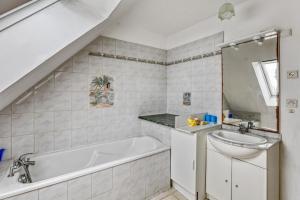 a bathroom with a bath tub and a sink at Charmante Maison en Campagne près de Nevez avec Jardin Clôturé in Névez