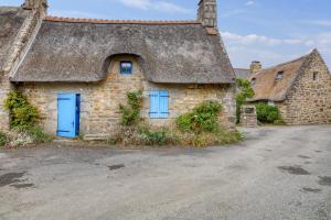 an old stone house with a thatched roof at Charmante Maison en Campagne près de Nevez avec Jardin Clôturé in Névez