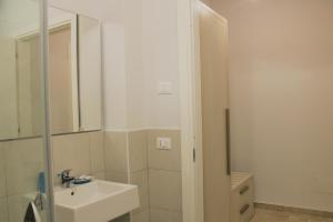 a white bathroom with a sink and a mirror at Zibibbo Beach Apartments - Trapani in Trapani