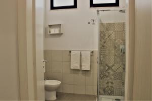 a bathroom with a toilet and a glass shower at Zibibbo Beach Apartments - Trapani in Trapani