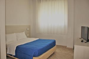 a bedroom with a bed with blue sheets and a television at Zibibbo Beach Apartments - Trapani in Trapani