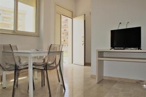 a dining room with a table with chairs and a television at Zibibbo Beach Apartments - Trapani in Trapani