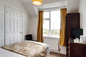a bedroom with a bed and a window and a television at Palm Court in Skegness
