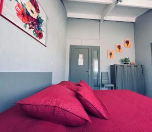 a red bed with red pillows in a bedroom at L organdi in Cornebarrieu