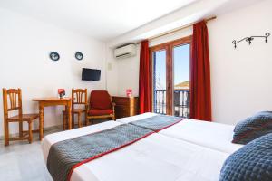 a bedroom with a bed and a desk and a window at Apartamentos Pepe Mesa in Nerja