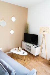 a living room with a couch and a tv and a table at Charmant appartement avec parking privé in Saumur