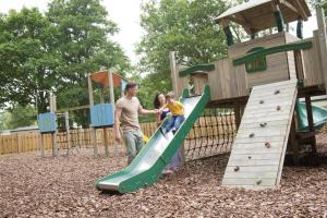 a man and a child playing on a slide at a playground at Oakdene -3 Bedroom Caravan in Weeley