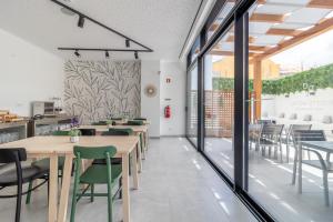 a restaurant with wooden tables and green chairs at Roots Hotel in Faro