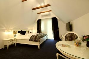 a white bedroom with a bed and a table at Casa Hermanni in Sibiu