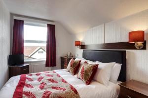 a hotel room with a bed with red and white pillows at Palm Court in Skegness