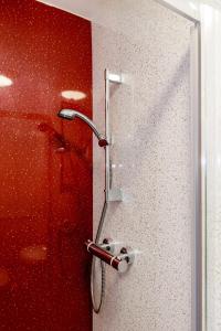 a shower in a bathroom with a red wall at Palm Court in Skegness