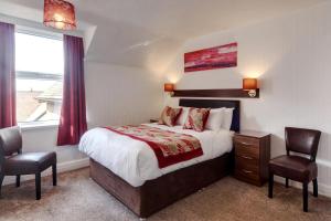 a bedroom with a bed and two chairs and a window at Palm Court in Skegness