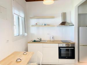 a white kitchen with a table and a refrigerator at Seaside Bungalows Petalidi in Petalidi